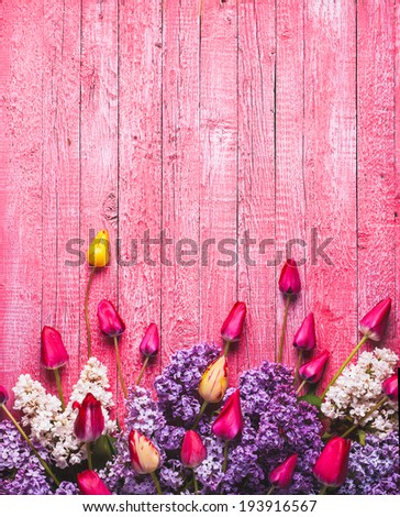 Various tulips and lilac on pink wooden background