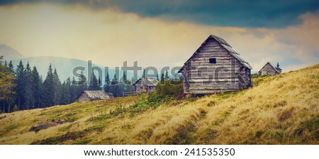 Sunrise above the nature wooden Ukrainian houses in a Carpathian mountains. Early misty morning, beginning of new day. Vintage colors