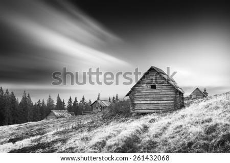 Sunrise above the nature wooden Ukrainian houses in a Carpathian mountains. Early morning, beginning of new day. Monochrome colors