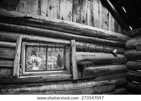 View from window of rustic wooden house to Carpathian mountain village. Ethnic cottage. Black and white.