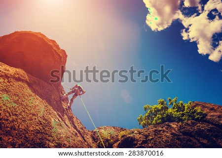 Rock climber on a cliff against the sky background. Vintage colors