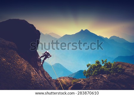 Silhouette of climber on a cliff against beautiful sunset in a high mountains