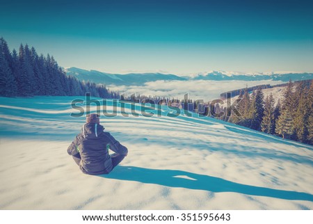 Hiker relaxing in a Carpathian mountain valley and enjoy majestic winter landscape. Ukraine, Europe. Vintage colors