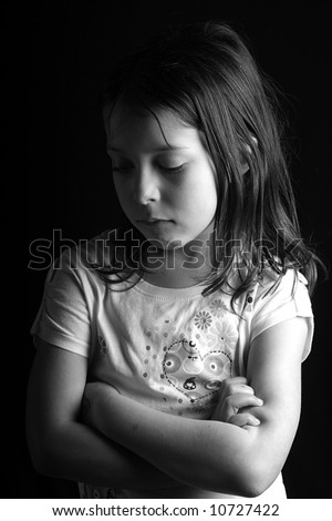 Shot of a pretty seven year old girl looking down with her arms crossed, against a black background II