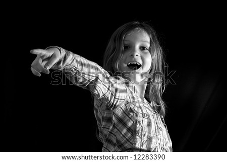 Young Girl Pointing Towards Camera against a Black Background