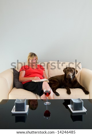 Senior Lady Relaxing on the Sofa with her Dog, a Book and a Glass of Wine