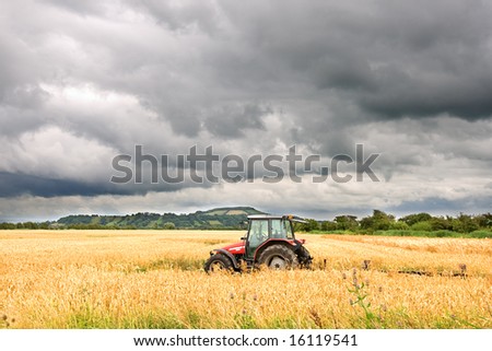 Tractor in Field under Threatening Rain Clouds