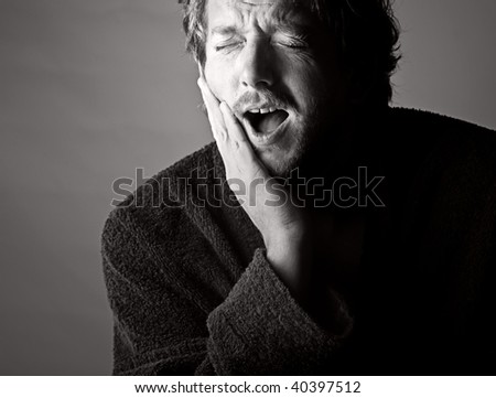 Dramatic Black and White Shot of a Man in Pain holding his Jaw. Toothache!