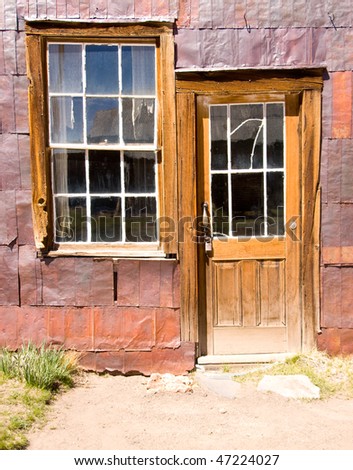 rusted, purple wall with a wooden window and door
