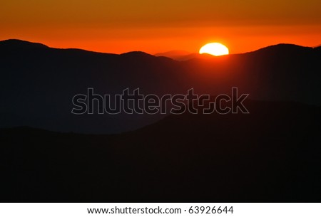 bright red sun rising over a mountain range
