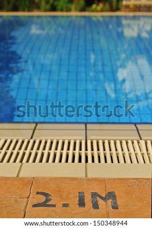 Close up of the edge of swimming pool and sign indicating the depth of the pool