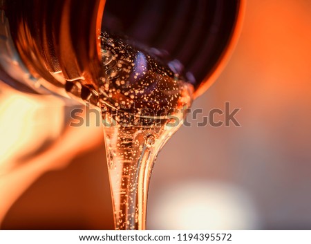 Liquid stream of motorcycle motor oil flows from the neck of the bottle close-up.