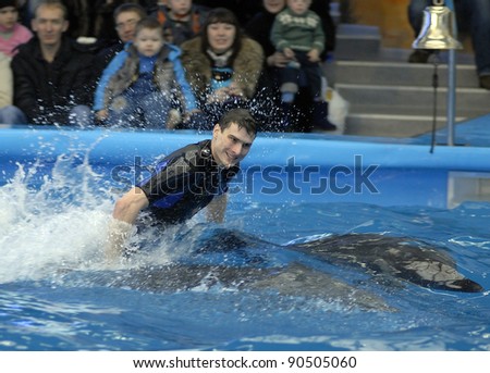 MINSK, BELARUS - DECEMBER 10: The trainer performs the trick with the dolphins during opening of the dolphinarium \