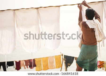 Indian old man hang the wash on a clothesline