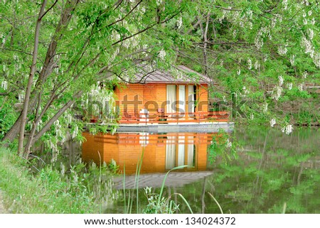 orange house on the calm lake surface into green forest