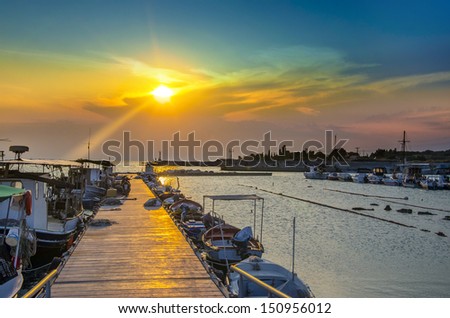 Fishing boat harbor at sunset. Colorful sunset sky shine over harbor boardwalk and boats, ships