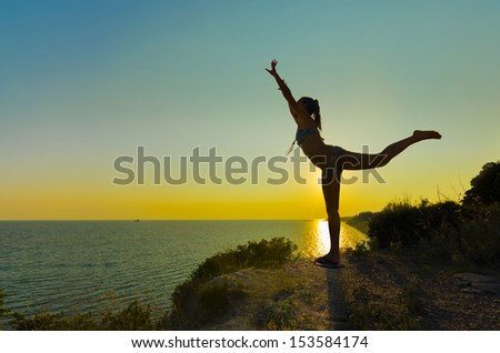 Silhouette of Joy. Silhouette of a gymnast backlit girl in balance on a beam at sunset against sea horizon