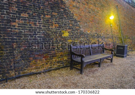 Old wooden benches in old alley with brick wall. Tower of London back street with litter bin