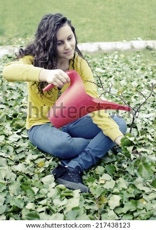 beautiful teenager yellow shirt girl water pouring small tree with red bucket