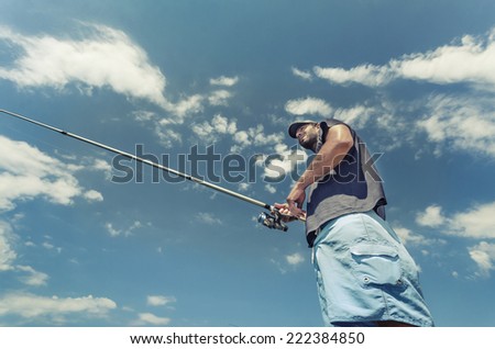 Fly Fisherman Casting. A fly fisherman roll casts a fly.Lower view on blue vibrant cloud sky