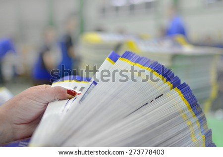Manual control and count of printed material packets with blur workers at background