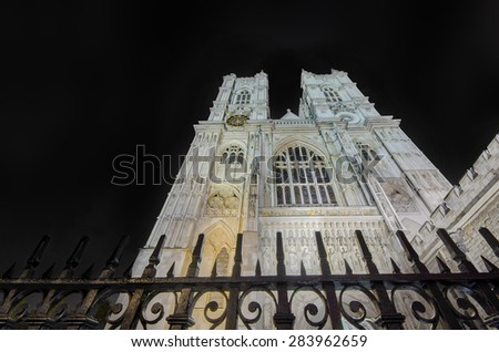 Westminster Abbey cathedral from below with dramatic sky, light post and fence, night shoot, London, United Kingdom