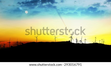 LOOP windmill turbines harnessing clean, green, wind energy silhouetted in the sunrise/sunset sky with sun rays. Green energy