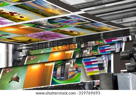 Magazine offset print production line. Large offset printing press running a long roll off paper over its rollers at high speed.