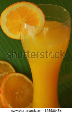 Orange juice in a glass on a banana leaf.