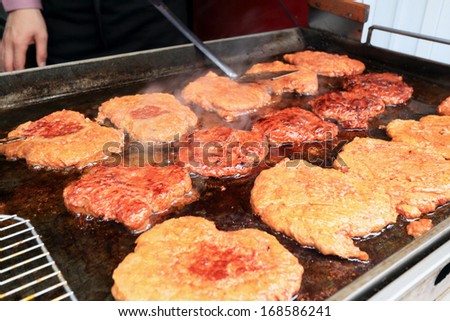 Fried steak on a hot pan on the market.