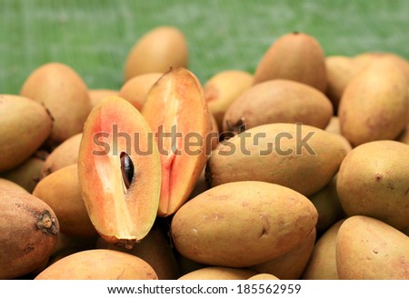 Sapodilla fruit pile in the background.