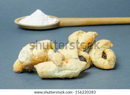Traditional crescent rolls with plum jam and a wood spoon with flour on the background