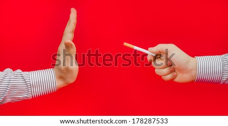 Give up smoking suggested by refusing cigarettes by a business man on a red alerted serious background with a dangerous unhealthy look
