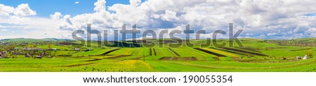 Panoramic view of  farm land with two villages on the side on a blue spring sunny day with a vibrant colorful look
