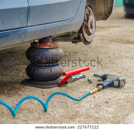 Dirty car and pneumatic tools at a service workshop for a tyre change on old concrete