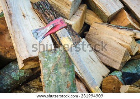Chopped lumber in a pile with a red axe suggesting fuel for heat in the cold season