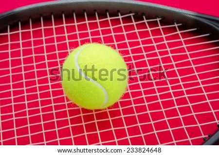 Tennis ball on a racket with a red alerted serious background suggesting an important match set game or point in this great elegant sport