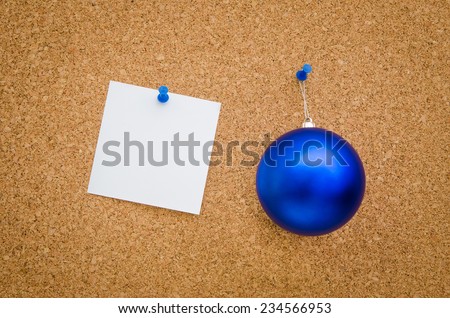 Blue christmas globe and white paper with text space pinned to a board suggesting a business office holiday christmas greeting card