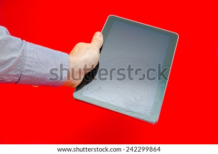Cracked touch screen display glass in a business man\'s hand on a red alerted background suggesting fragile electronics and fix and repair on expensive technology with an alerted look