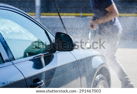 Man washing his car and pulverizing water all over with a dynamic look suggesting car wash services on a premium auto vehicle