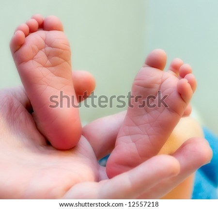 Two week old baby feet held in mothers hand.