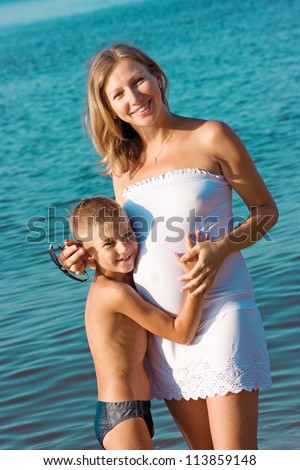 Pregnant mother and son hugging and smiling