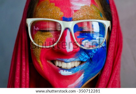 smiling woman completely covered with thick paint and wearing white rim glasses