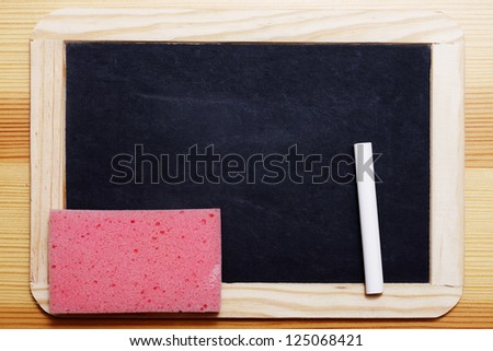 Empty Black board with piece of chalk and a pink sponge.