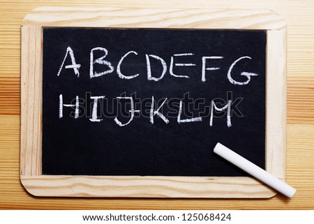 Empty Black board with first half of the alphabet written in chalk.