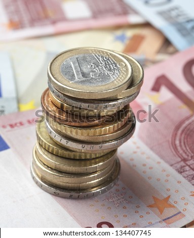 Background of Euro banknotes with coins standing on top. Short Depth of field with front and back part blurred out of focus.