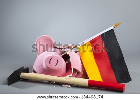 Broken piggy bank with German flag and hammer