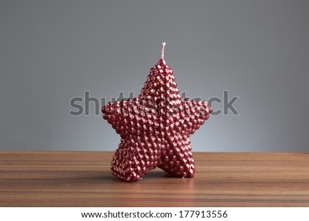 Single purple candle in shape of a star on a wooden table.