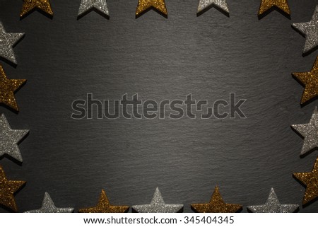Frame of golden and silver stars on slate texture background, christmas decoration.