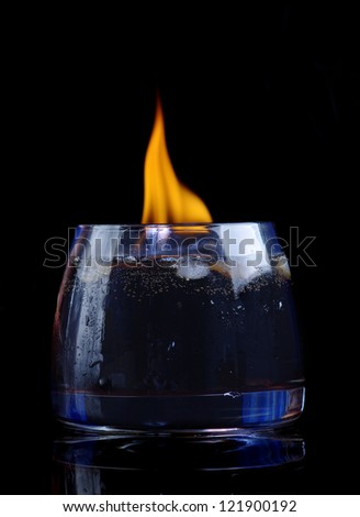 cola with cognac and fire in glass on black